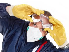 Ein Mann trägt Gummihandschuhe, eine Schutzbrille und eine Maske.