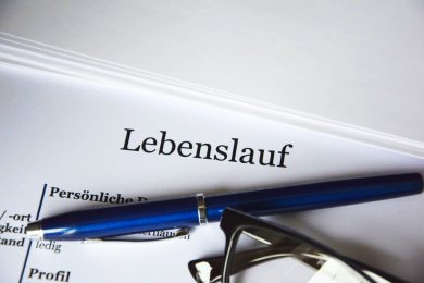 Papier mit Aufschrift Lebenslauf, einem Kugelschreiber und einer Brille