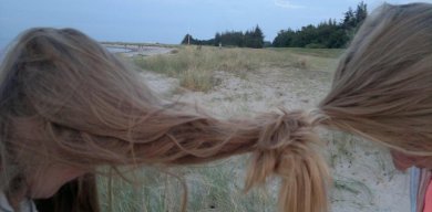 Zwei Mädchen auf einer Wiese, deren Zöpfe miteinander verhedderd sind