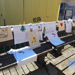 Selbst gestaltete T-Shirts hängen über einem Geländer