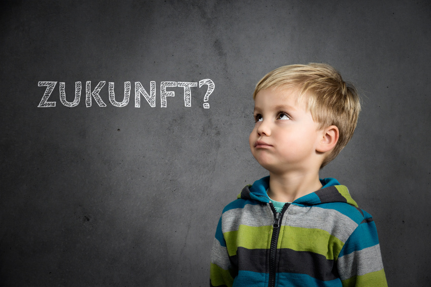 Ein Junge schaut nach oben links zu einer Tafel. Auf der steht das Wort Zukunft?