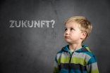 Symbolbild Zukunft Ein Junge schaut nach oben links zu einer Tafel. Auf der steht das Wort Zukunft?