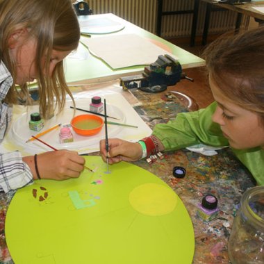 zwei junge Mädchen malen an einem Tisch ein Motiv für das Kunstwerk.