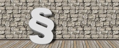 Steinmauer im Hintergrund und ein  weißes Paragraphenpiktogramm im Vordergrund