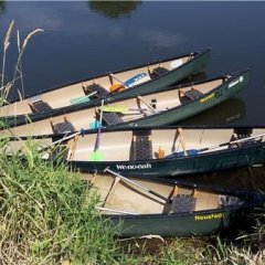 4 leere Kanus am Ufer eines Gewässers