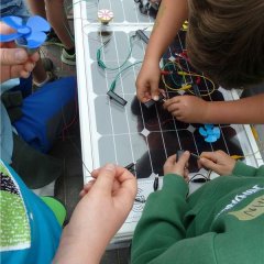Kinder lassen einen Ventilator mit Hilfe von Kabelverbindungen an einer Solarzelle laufen