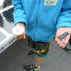 Kind steht neben Solarbank und hält Kabel in der Hand