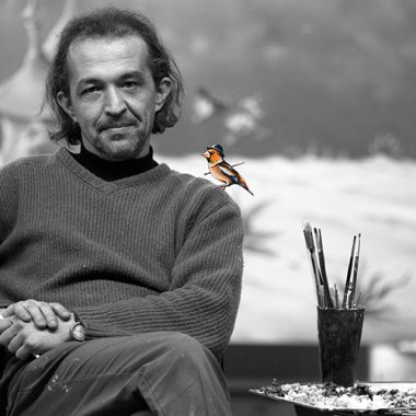 Portrait Marek Konarski Schwarz-weiß Foto Marek Konarski, er sitzt auf einem Stuhl, hat die Beine überschlagen und schaut in die Kamera