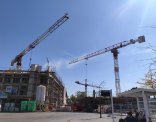 Bau des NeuStadtTors Baustelle des Projektes NeuStadtTor mit eingerüsteten Gebäudeteilen und drei Kränen. Im Vordergrund warten mehrere Personen an einer Bushaltestelle.
