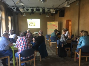 Raum mit Teilnehmenden die sich eine Präsentation anschauen