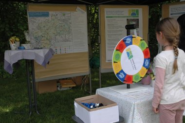 Junges Mädchen steht vor einem Drehrad am Stand Leader-Region Meer und Moor