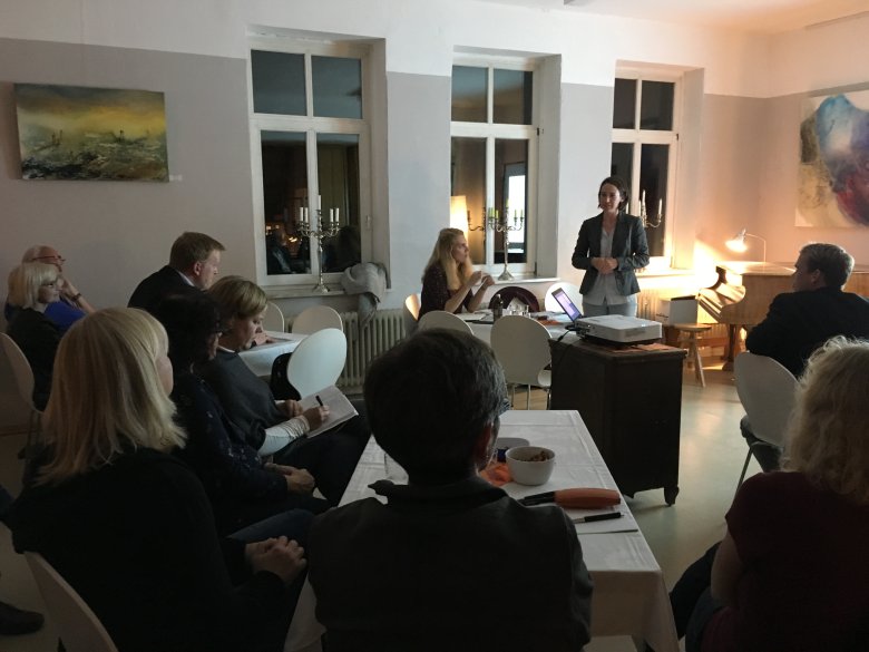 Teilnehmerin hält eine Rede und Teilnehmer machen sich Notizen