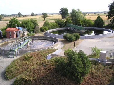 Blick von oben auf die Kläranlage in Basse mit zwei großen Klärbecken im Vordergrund