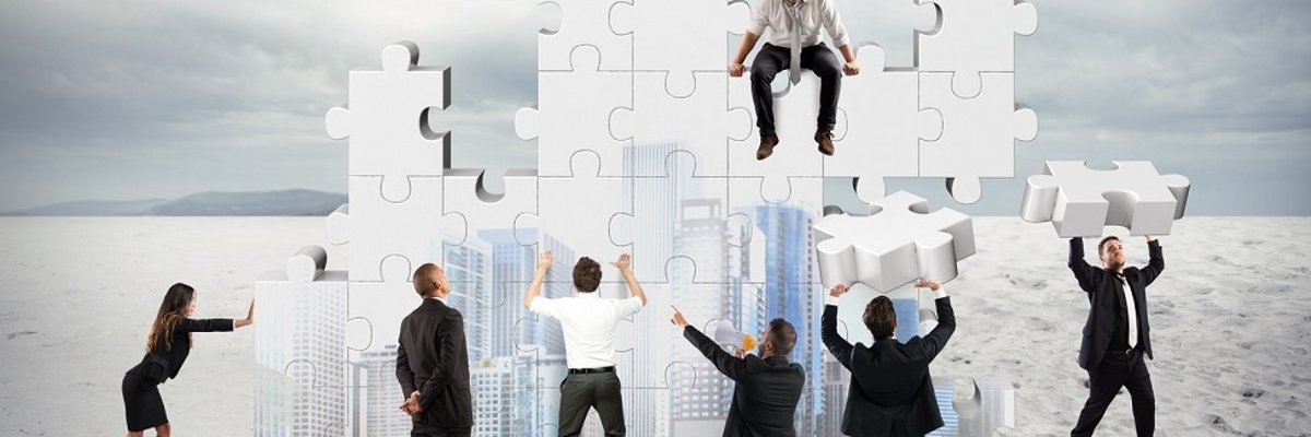 Sieben Personen bauen mit großen Puzzleteilen ein neues Unternehmen zusammen