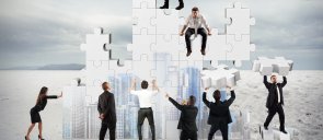 Sieben Personen bauen mit großen Puzzleteilen ein neues Unternehmen zusammen