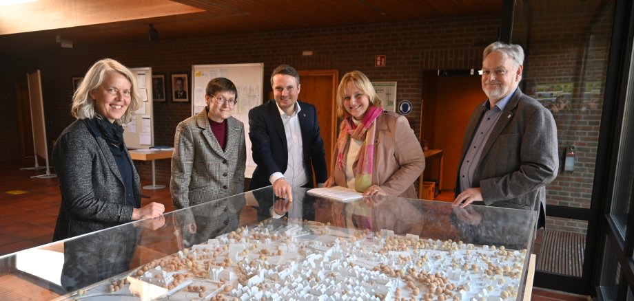 Übergabe Förderbescheid ArL Fünf Personen stehen vor dem Modell der Neustädter Innenstadt im Foyer vor dem Sitzungssaal und lächeln in die Kamera.