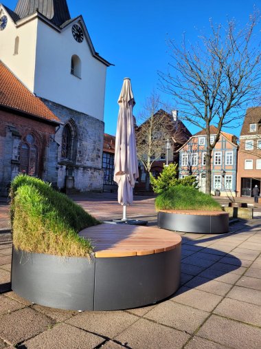 Pressefoto Sitzmöbel Abgekühlt Zwei runde Sitzmöbel mit grünen Sonnenverdecks in Blätteroptik stehen vor der Alten Wache in der Marktstr. in der Mitte steht ein zusammengeklappter Sonnenschirm.