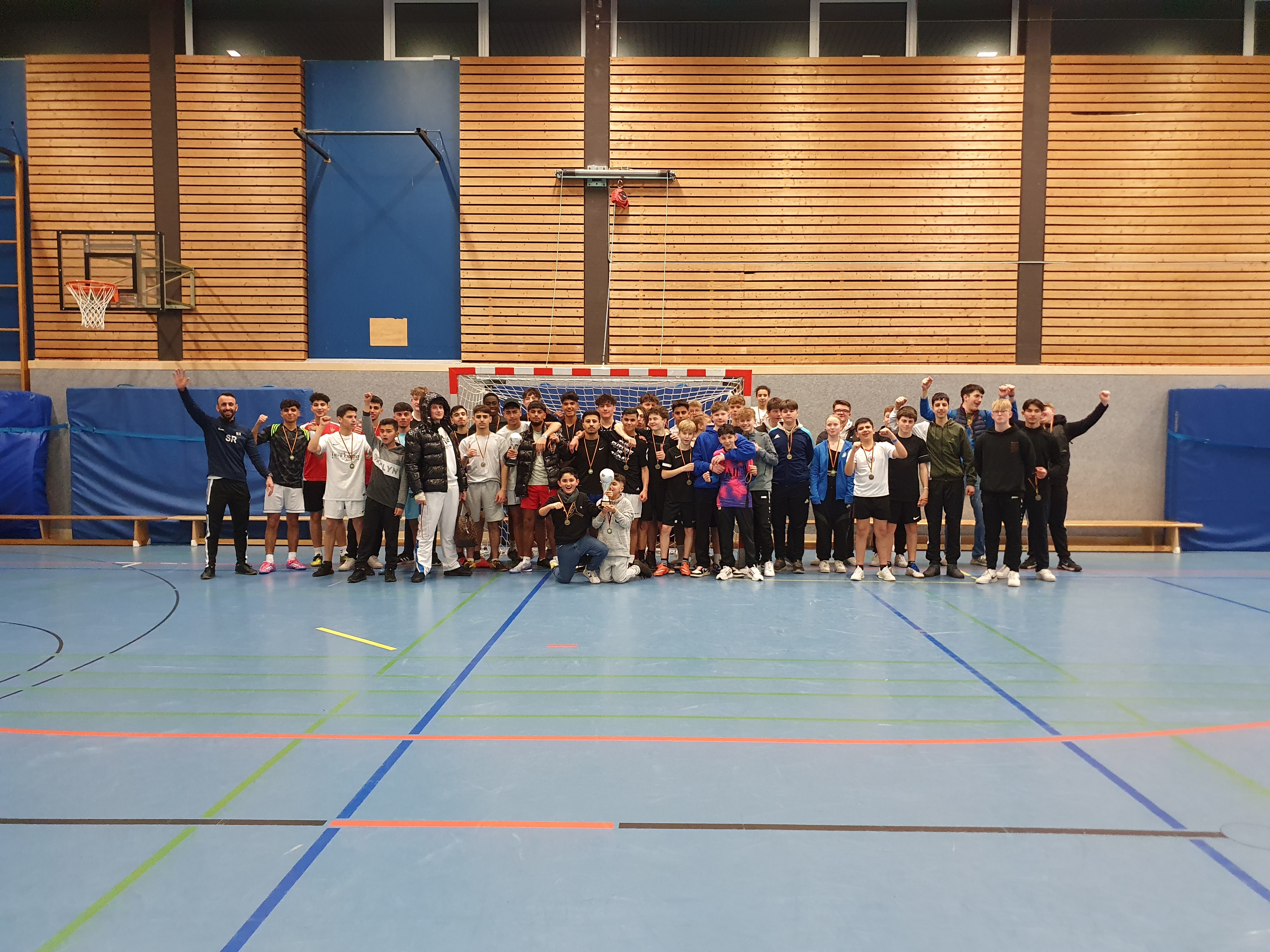 Eine große Gruppe von jugendlichen Fußballspielerinnen und -spielern steh in der Sportahlle vor dem Tor. Alle Lächeln in Richtung Kamera.