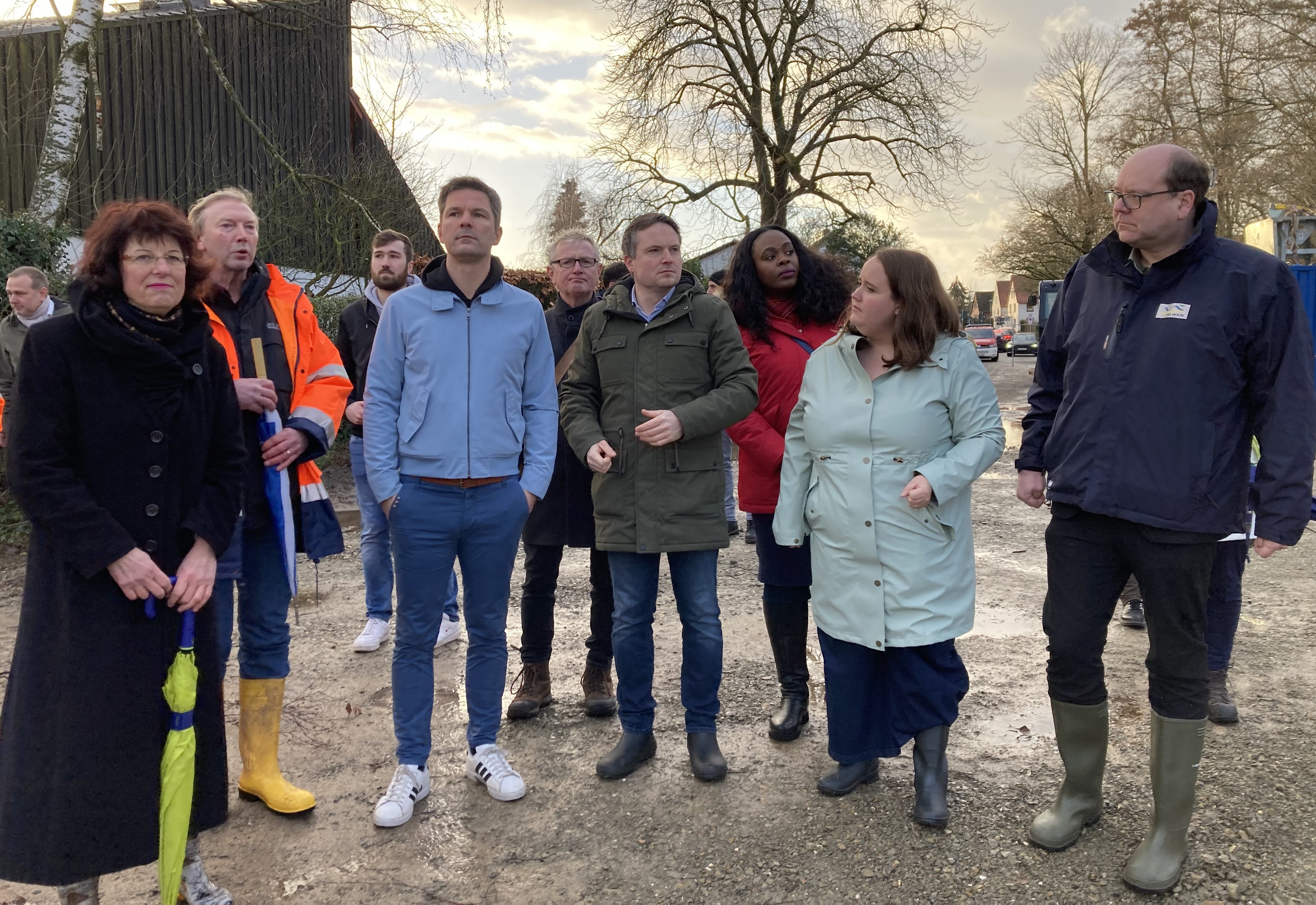 Mehre Personen stehen im Halbkreis an der Deichbaustelle im Silbernkamp.
