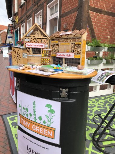 Nahaufnahme Insektenhotes Auf einem Infotisch stehen verschiedene Insektenhotels. einige dienen als Negtaivbeispiele und sind mit einem Hinweisschild So bitte nicht vershenen. Dazu liegen Infoflyer aus.