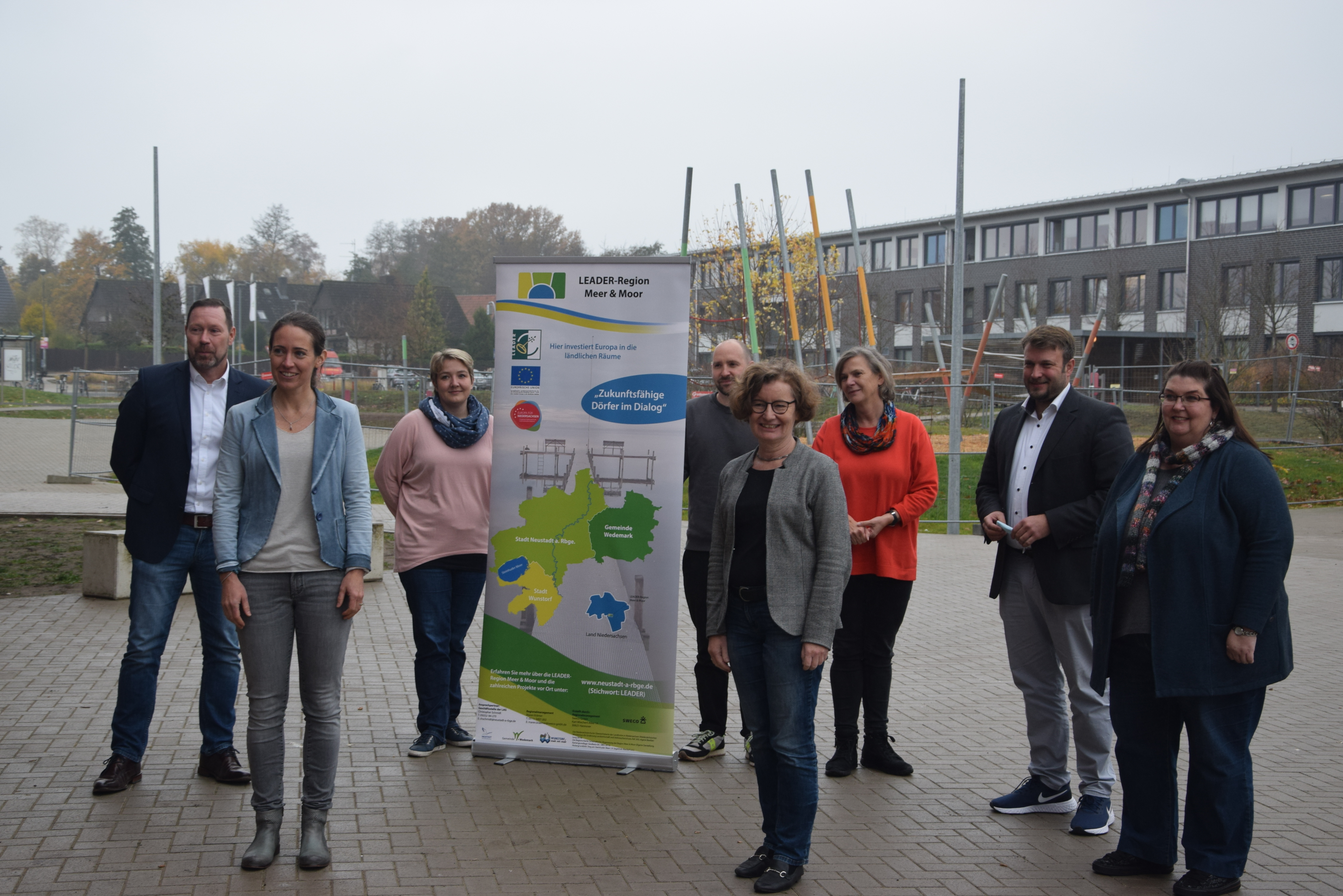 Mitarbeitender der LEADER-Region stehen vor einem Roll-Up draußen vor einem Gebäude.