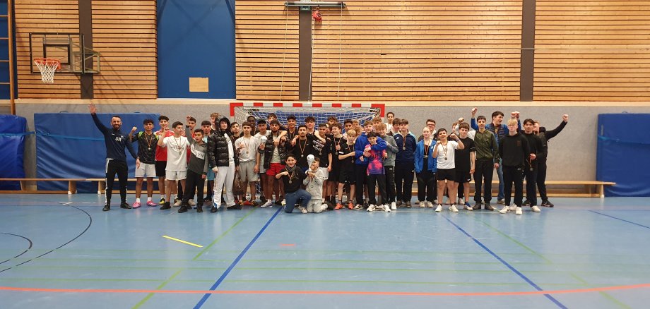 Teilnehmende Nuetsädter Fußball Cup 2023 Eine große Gruppe von jugendlichen Fußballspielerinnen und -spielern steh in der Sportahlle vor dem Tor. Alle Lächeln in Richtung Kamera.