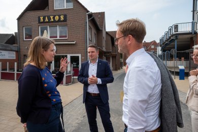 Pressefoto Fahrradstraße Frau Hamburg (li.), Herr Herbst (mi.) und Herr Homeier (re.) stehen im Kreis auf dem fertigen Teilstück der Fahrradstraße und sind in ein Gespräch vertieft.