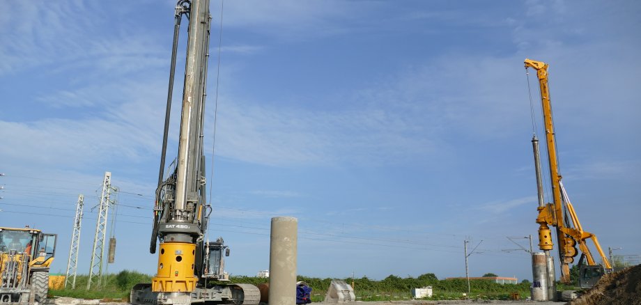 Blick auf die Baustelle für die Brücke über die Bahngleise in der Kernstad. zwei 20 Meter hohe Bohrmaschinen und ein Bagger sind zu sehen.
