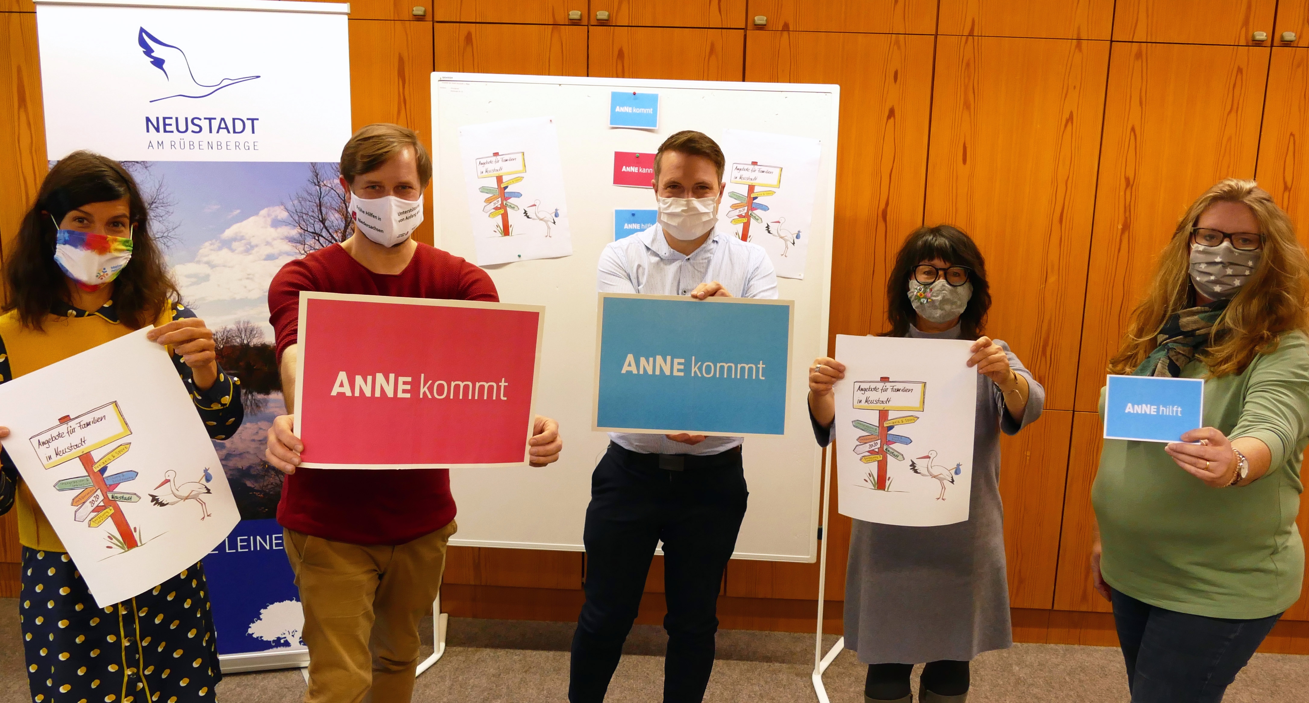 Fünf Personen halten Plakate in die Kamera, auf denen steht Anne kommt. Alle tragen einen Mund-Nasen-Schutz.