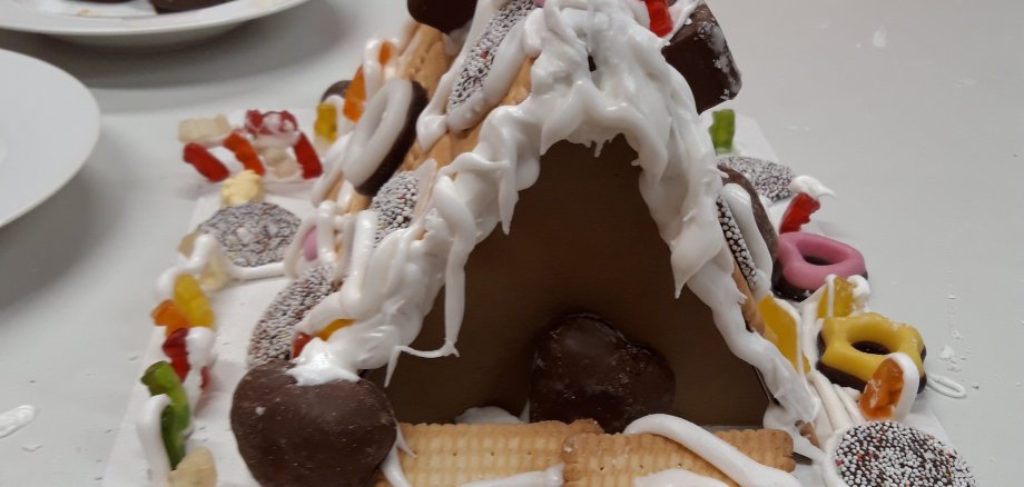 Nahaufnahme eines Lebkuchenhauses, das mit Süßigkeiten verziert ist.