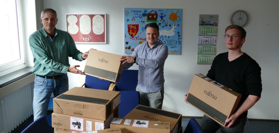 Bürgermeister Dominic Herbst lässt es sich nicht nehmen, die ersten Laptops aus dem Sofortausstattungsprogramm persönlich zu überreichen. Auf dem Bild von links nach rechts: Stefan Herholz, Gymnasium Neustadt, Bürgermeister Dominic Herbst und Norman Heine, IT Stadt Neustadt.