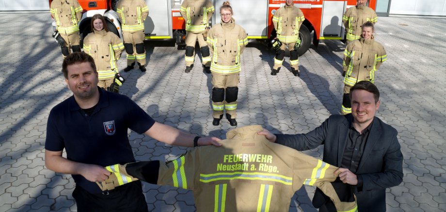 vorn rechts Torben Klingemann mit Bürgermeister Dominic Herbst. Im Hintergrund präsentieren Feuerwehrleute aus dem ganzen Stadtgebiet ihre neue Ausrüstung. In der mittleren Reihe von links: Sara Storbeck (FW Eilvese), Ida Schom-burg (FW Nöpke) und Rabea Hatesaul (FW Nöpke). In der hinteren Reihe von links: Dennis Schumann (FW Eilvese), Jan Wiegand (FW Poggenhagen), Luis Neugebauer (FW Bordenau), Alessandro Stade (FW Esperke) und Manfred Walter (FW Laderholz). (c) Stadt Neustadt a. Rbge.de  