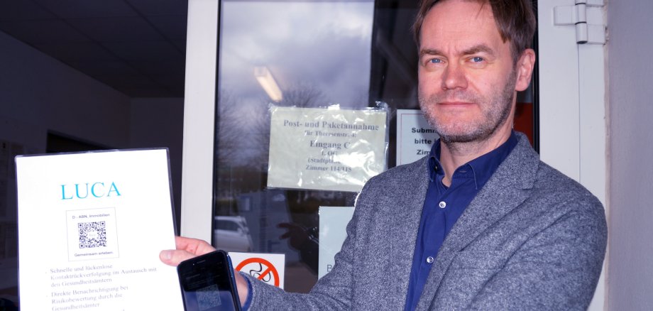 Fachbereichsleiter 3 Jörg Homeier hält in seiner Hand den QR-Code und ein Handy mit der luca App