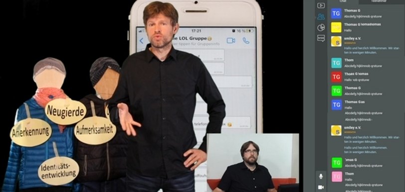 Screenshot eines Online-Seminars. Ein Mann steht vor einem übergroßen handy, links von ihm ein Schaubild. Unten rechts ist ein weitere Bildausschnitt mit einem weiteren Mann mit Headset am PC.