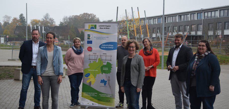 Mitarbeitender der LEADER-Region stehen vor einem Roll-Up draußen vor einem Gebäude.