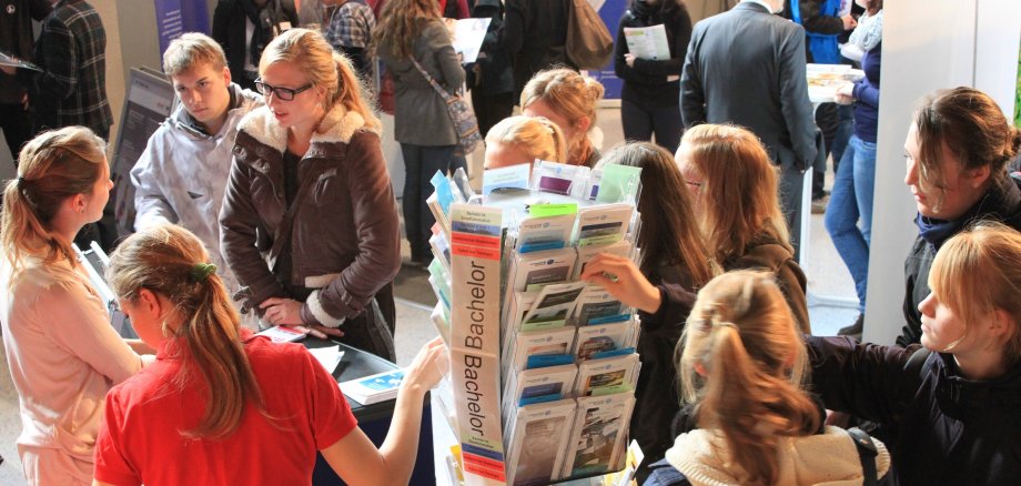 Schülerinnen und Schüler stehen an einem Infostand auf einer Messe