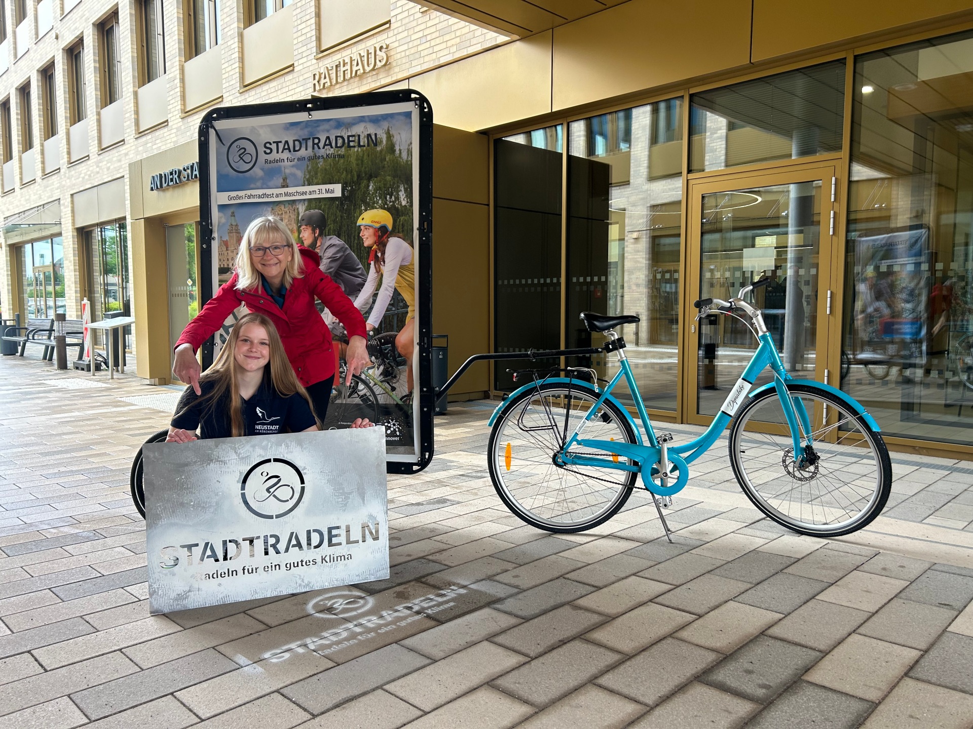 Hanna Uhde und Ulrike Ahrbecker von der Stadtverwaltung sprühen vor dem Rathaus das erste „Stadtradeln“-Logo auf den Boden. Die Logos mit Sprühkreide werben für eine Teilnahme an dem 21-tägigen Wettbewerb.