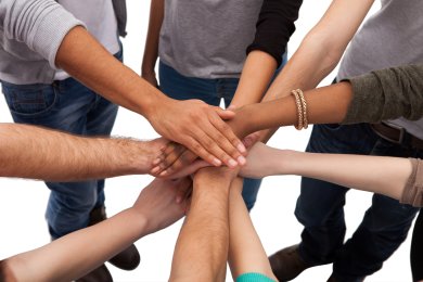 Symbolbild Integration und Gemeinschaft Hohe Winkelansicht von aufgestapelten Händen mit verschiedensten Hautfarben vor weißem Hintergrund