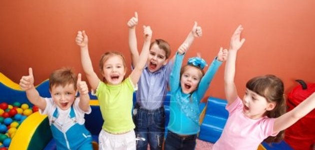 Gruppe Kinder zu sehen sind fünf Kinder, die lachend die Arme heben