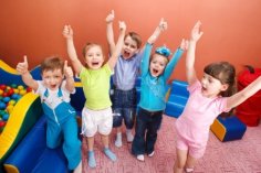 zu sehen sind fünf Kinder, die lachend die Arme heben