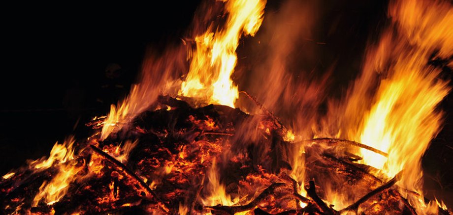 Symbolbild Osterfeuer Nahaufnahme eines brennenden Haufens aus Ästen und Zweigen. Der Himmel ist nachtschwarz