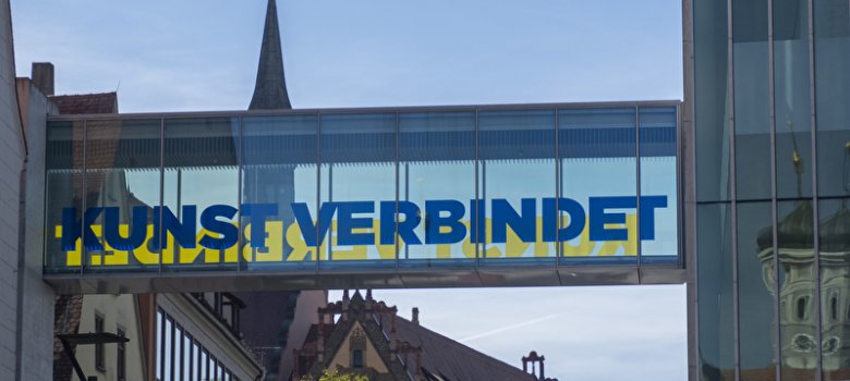 es wird einen Glasbrücke mit der Aufschrift "Kunst verbindet" gezeigt