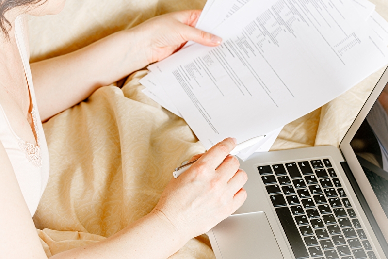 Nahaufnahme von einer jungen Person, die mit einem Laptop auf den Schoss arbeitet.