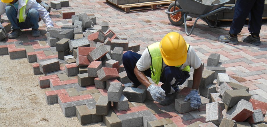 Symbolbild Pflasterarbeiten Ein Arbeiter pflastert eine Straße.