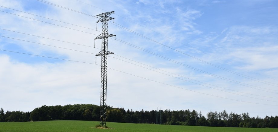 Symbolbild Stromleitung Land Aufnahme eines Strommasten mit Oberleitung im ländlichen Raum auf einer grünen Wiese