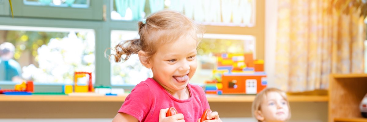 Symbolbild Kindergarten Kita Kleine Mädchen reiten auf Spielpferden im Kindergarten