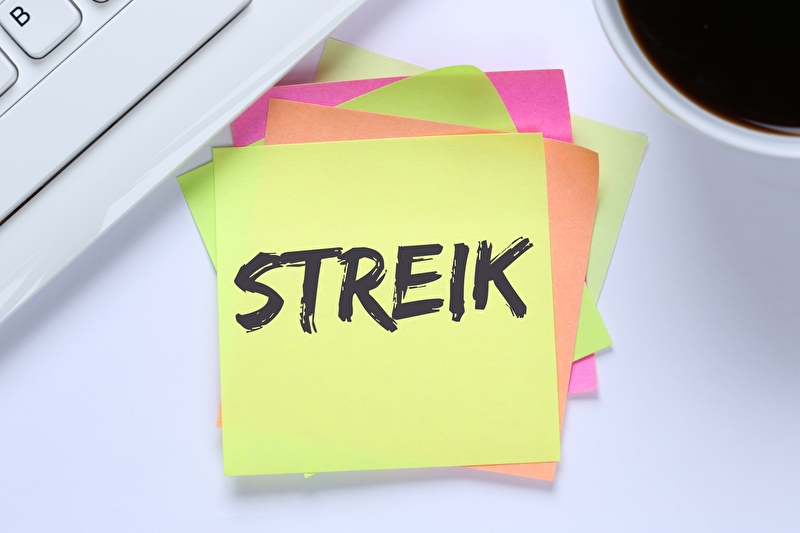Ein Notizzettel mit dem Wort Streik liegt auf einem Schreibtisch.