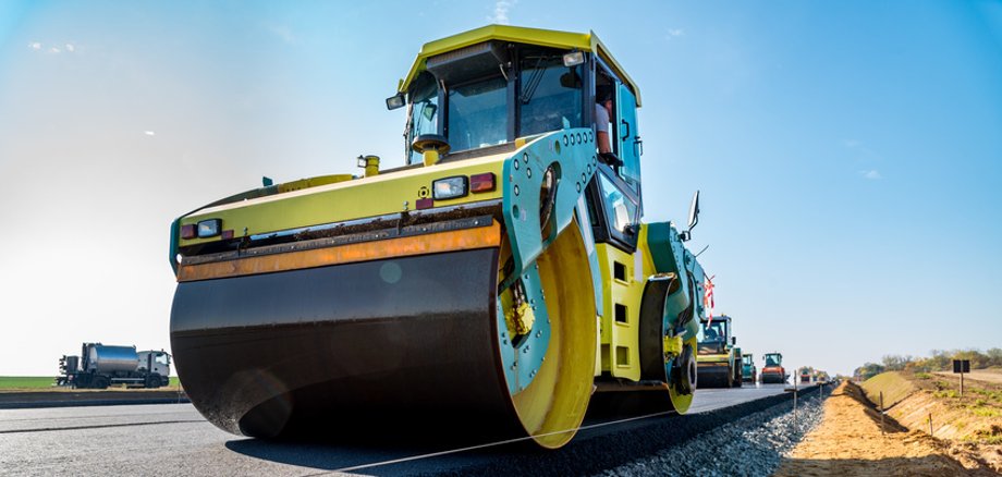 Symbolbild Straßenbau zu sehen ist eine Maschine, die über eine Straße rollt