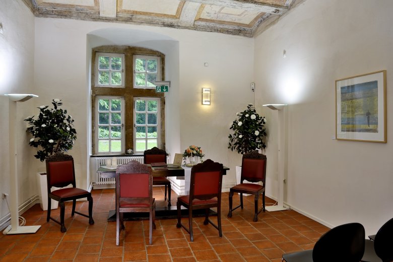 Trauzimmer im Schloss Landestrost Blick ins Trauzimmer des Schlosses. Trautisch mit Bestuhlung für Standesbeamtin, Brautpaar und Trauzeugen,. Im Hintergrund ein Fenster mit Blick in den Schlossgarten.