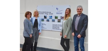 Vier Personen aus dem Team der Wirtschaftsförderung vor einem Schild